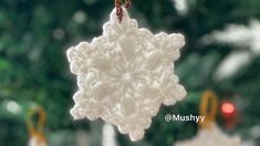 a crocheted snowflake ornament hanging from a christmas tree