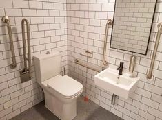 a white toilet sitting next to a sink in a bathroom under a mirror on the wall