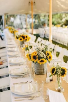 a long table is set with sunflowers and place settings