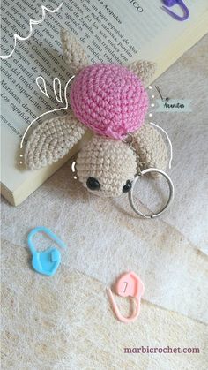 a crocheted stuffed animal with a pink hat on it's head sitting next to a pair of scissors