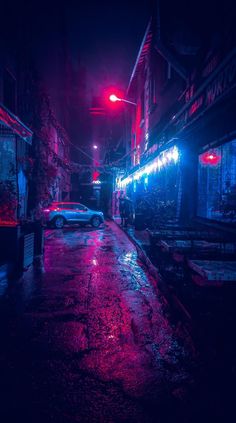 a car parked on the side of a street at night with red lights shining down