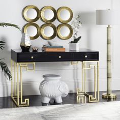 a black and gold console table with four round mirrors on it's wall above it