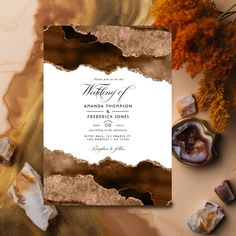 an elegant wedding card with gold foil on it and marbled paper in the background