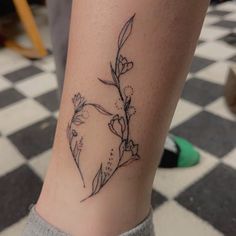 a tattoo on the leg of a woman with flowers and leaves drawn on her arm