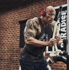 a man with headphones on holding onto a rope in front of a brick building