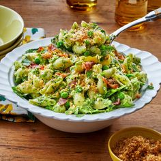 a white bowl filled with broccoli salad on top of a wooden table next to bowls