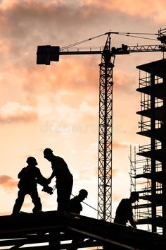 two construction workers shaking hands on top of a building under construction at sunset royalty photo