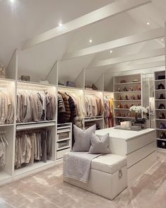 a large closet filled with lots of clothes and shoes next to a white couch on top of a carpeted floor