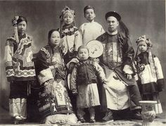 an old black and white photo of people in traditional chinese dress, with one child standing between two adults