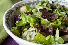 a white bowl filled with lettuce on top of a purple place mat