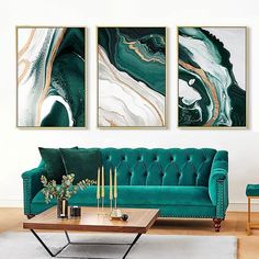 a living room filled with green couches and paintings on the wall above them,