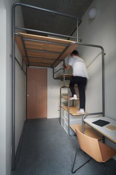 a man is climbing up the stairs in his loft bed, which also has a desk and chair