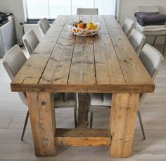 a wooden table with chairs around it and a bowl of fruit sitting on top of it