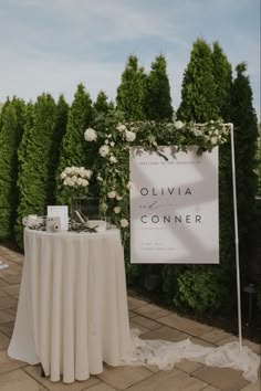 a table with white flowers on it and a sign that says ollivia conner