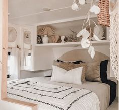 a bed with white linens and pillows in a room that has shelves on the wall