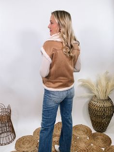 Camel Tan Suede Vest with Sherpa Trim Upgrade your winter wardrobe with our Camel Tan Suede Vest with Sherpa Trim. This chic vest is perfect for a stylish snow day outfit, offering a luxurious look and feel that will make you stand out. The soft suede material in a rich camel tan color is complemented by plush fur trim at the edges, giving it a high-end, sophisticated vibe. With a zipper front and side pockets, this vest combines practicality with elegance. The relaxed fit ensures comfort, makin Beige Vest For Cold Weather And Winter, Beige Vest For Cold Weather In Winter, Beige Vest For Winter Cold Weather, Beige Winter Vest For Cold Weather, Casual Brown Vest For Winter, Trendy Winter Vest For Layering, Beige Vest For Layering, Beige Vest For Cold Weather In Fall, Trendy Cold Weather Vest Outerwear