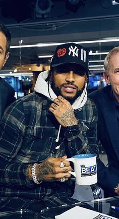 two men sitting next to each other at a table with coffee mugs in front of them