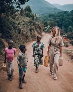 two women and three children walking down a dirt road