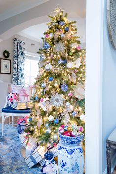 a decorated christmas tree in the corner of a living room with blue and white decor