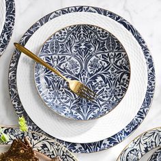 blue and white plates with gold utensils are arranged on a marble table top