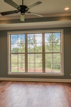 an empty room with wood floors and a ceiling fan in the middle of the room