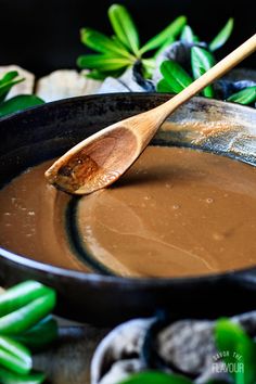 a wooden spoon stirring chocolate in a skillet with green leaves and rocks on the side