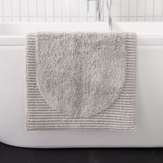 a white bath tub with a towel hanging on it's side in a bathroom