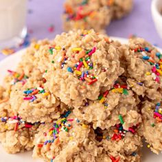 cookies with sprinkles on a white plate next to a glass of milk