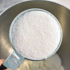 a person holding a measuring spoon with some white powder in it's side dish