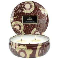 a candle that is sitting in front of a white background with brown and gold designs on it