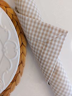 a white plate sitting next to a brown and white checkered napkin on top of a table