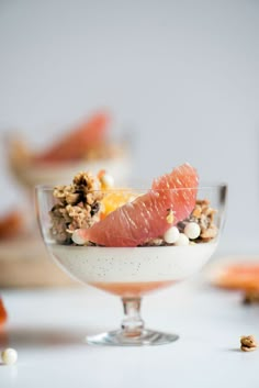 a bowl filled with granola and fruit on top of a white table next to other food items