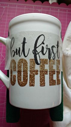 a coffee cup with the words but first coffee written on it and gold glitters