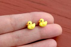 two tiny yellow rubber ducks sitting on someone's finger