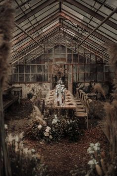 an old greenhouse with tables and chairs in the center, surrounded by tall grass and flowers