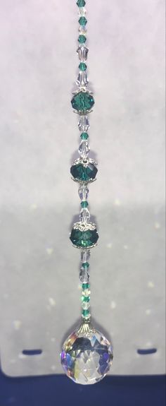 a glass bead hanging from the ceiling in front of a white background with blue and green accents