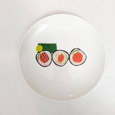 a white plate topped with sushi cut in half on top of a white table