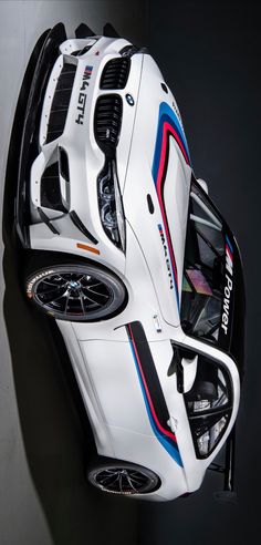 the front end of a white sports car with red, blue and black stripes on it