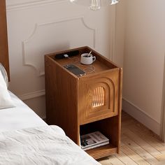 a nightstand with a phone on it next to a bed