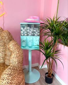 a room with pink walls and wicker furniture, including a chair and potted plant