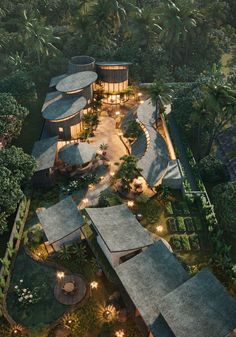 an aerial view of a house in the middle of trees with lights shining on it