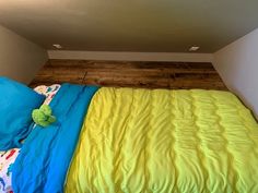 a bed with blue and yellow sheets in a room next to a wooden flooring wall