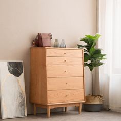 a wooden dresser sitting next to a window in a room with a plant on top of it