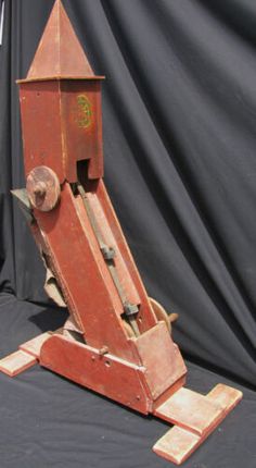 an old wooden machine on display in front of a black backdrop