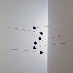 an abstract sculpture with black balls and red dots hanging from it's center wall