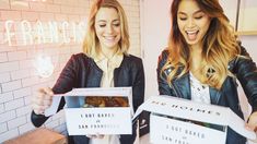 two women holding up boxes with donuts in them and the words i got baked on them