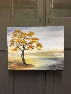 a painting hanging on the side of a door with a tree painted on it's front