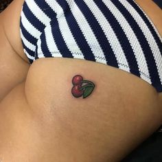 a small cherry tattoo on the side of a woman's stomach is shown in black and white stripes