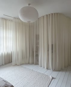 a white bedroom with sheer curtains on the windows