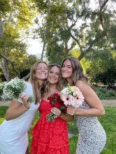 three beautiful young women standing next to each other holding bouquets of flowers in their hands